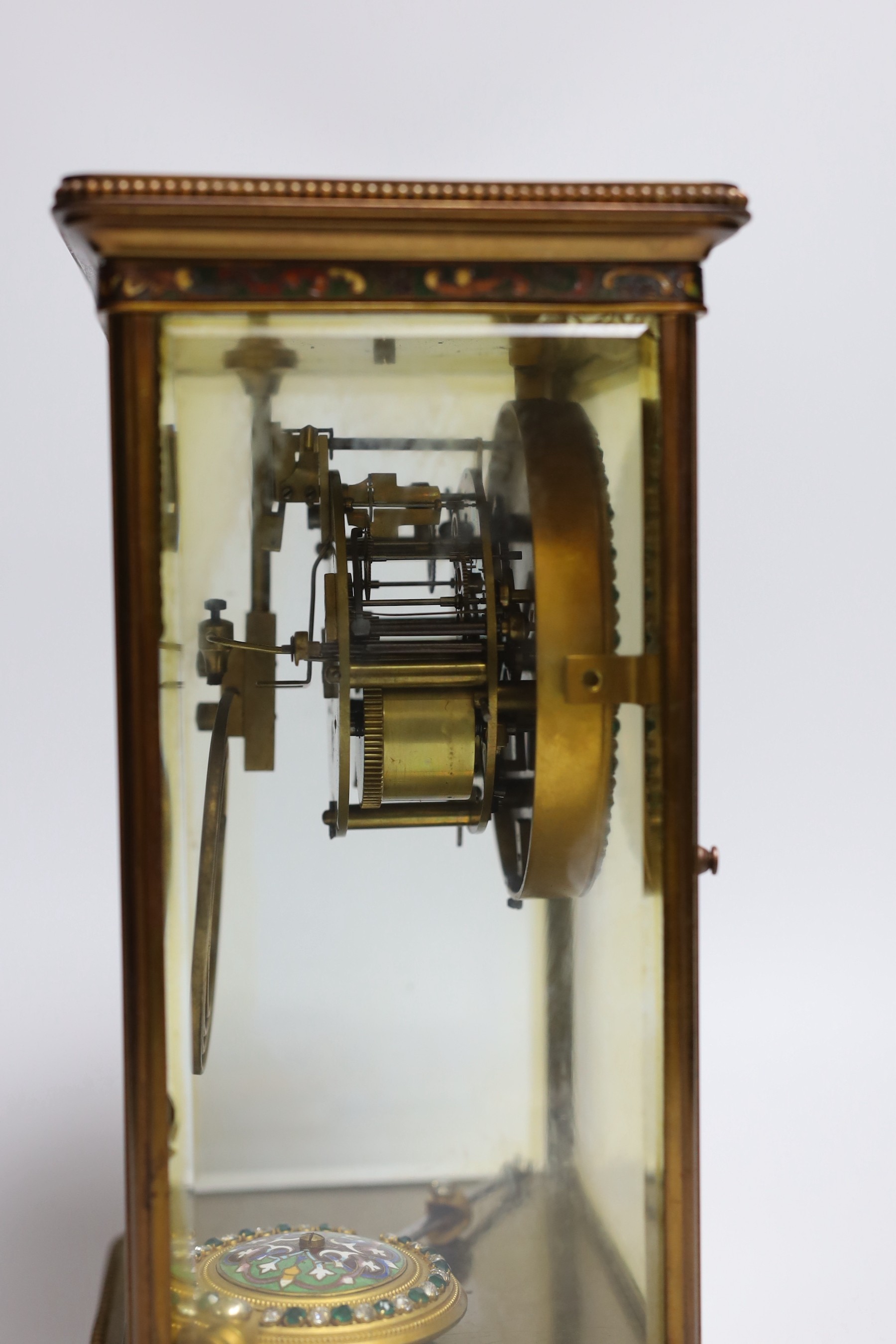 An early 20th century four glass brass and champleve enamel clock, with decorative enamelled and paste dial and pendulum, 7cms wide, 28cms high